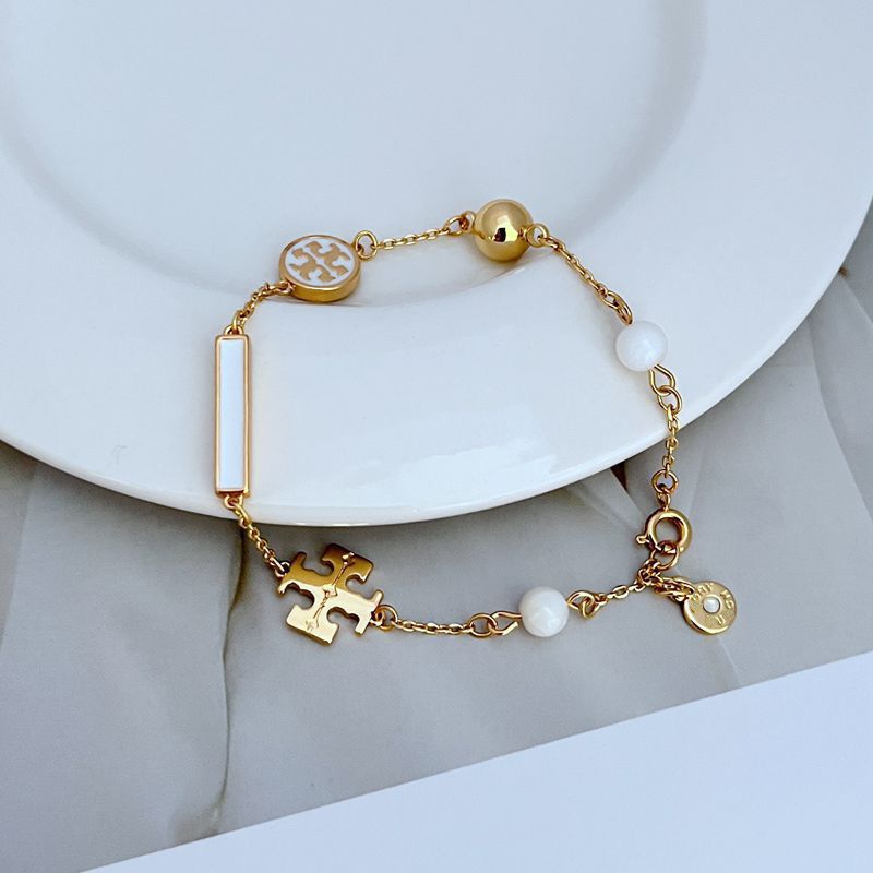 Bracelet laid in a naturally scattered, curved shape on a textured neutral background, highlighting the asymmetric placement of beads and charms.