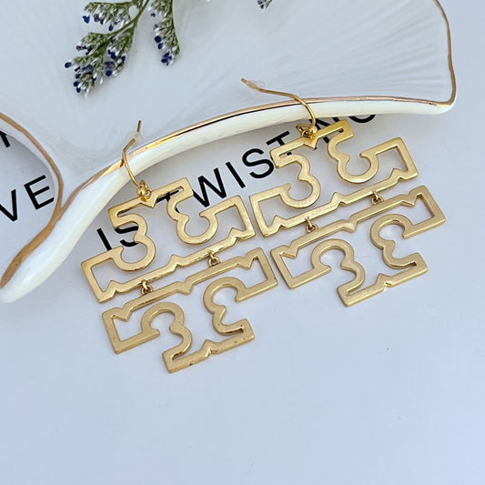 Both earrings displayed front-facing on a clean, neutral background, emphasizing their substantial size and iconic logo shape.
