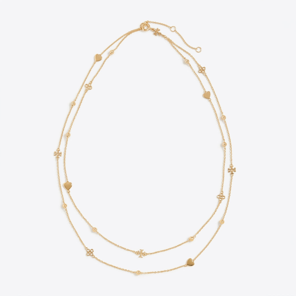 A delicate double-strand gold necklace featuring small heart and flower charms, displayed on a clean, light gray background.