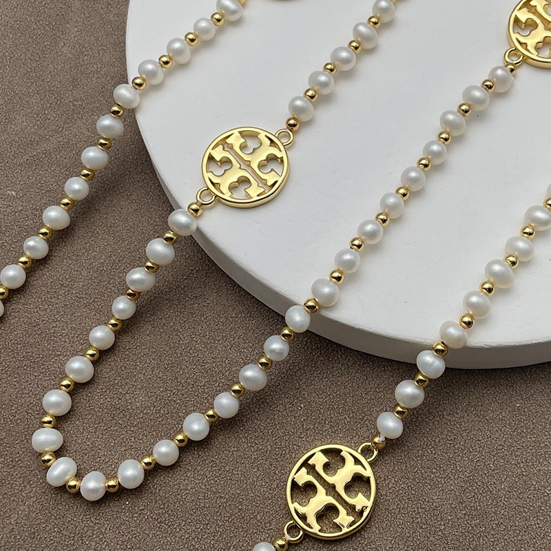 Necklace laid flat in a draped or straight line, clearly showing the repeating logo charms and the cross pendant at the center or end.