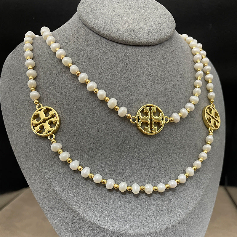 Necklace laid flat in a draped or straight line, clearly showing the repeating logo charms and the cross pendant at the center or end.