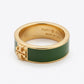A gold-tone ring with a wide dark green enamel band and a gold-tone Tory Burch logo on the front, shown on a clean white background.