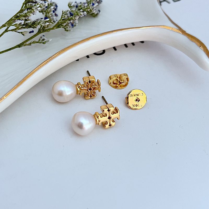 Clean, vertical shot of a single earring against a soft, neutral background, clearly showing the Double T logo above the pearl drop.