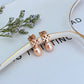 Clean, vertical shot of a single earring against a soft, neutral background, clearly showing the Double T logo above the pearl drop.