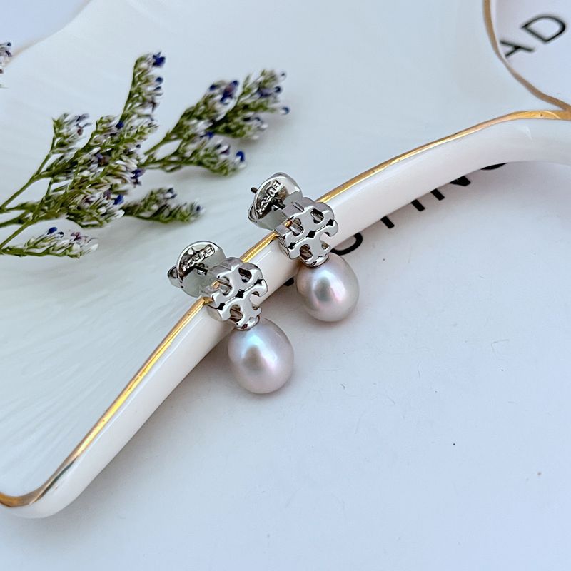  Macro view focusing on the engraved details of the Double T logo and the smooth, luminous surface of the pearl.