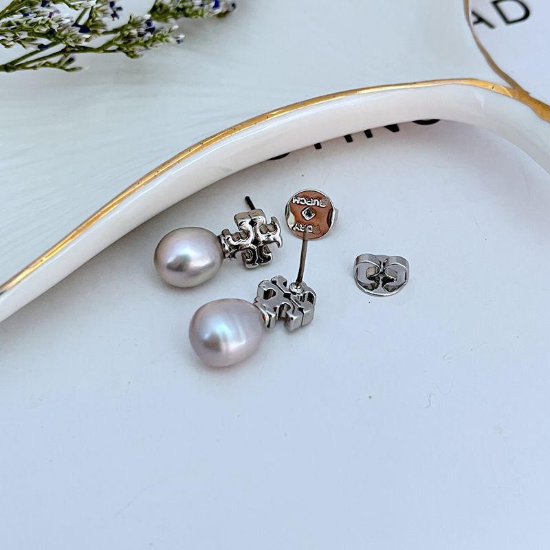  Macro view focusing on the engraved details of the Double T logo and the smooth, luminous surface of the pearl.
