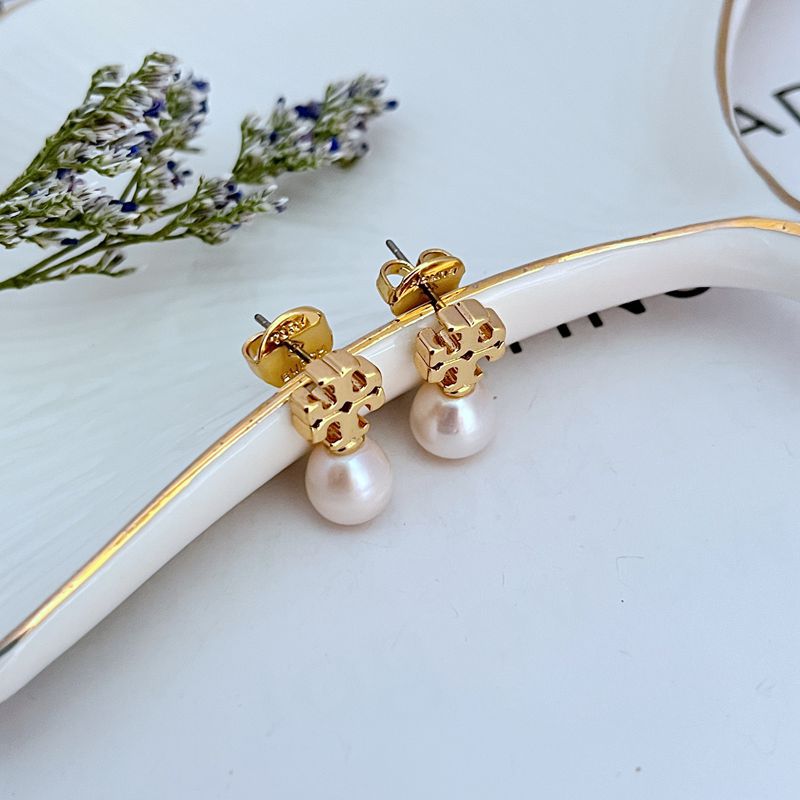 Clean, vertical shot of a single earring against a soft, neutral background, clearly showing the Double T logo above the pearl drop.
