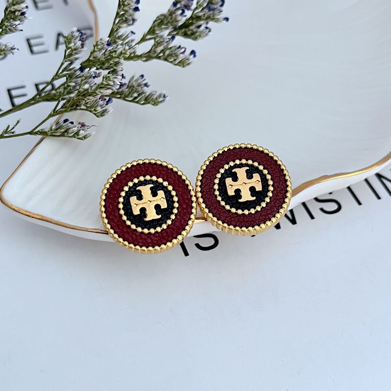 Clean, sharp shot of a single stud against a neutral background, highlighting the clear contrast between the shiny metal logo and the matte, grained texture of the leather inlay.