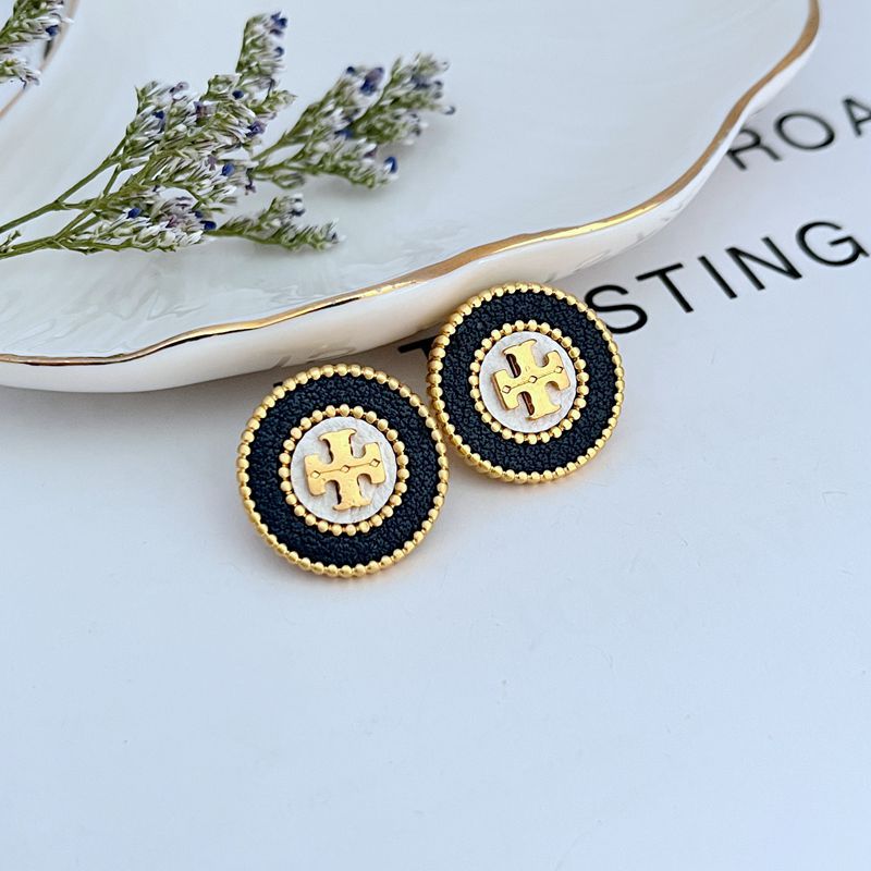 Clean, sharp shot of a single stud against a neutral background, highlighting the clear contrast between the shiny metal logo and the matte, grained texture of the leather inlay.