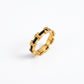 A gold ring with a repeating interlocking H-pattern design filled with black inlay, shown on a clean white background.