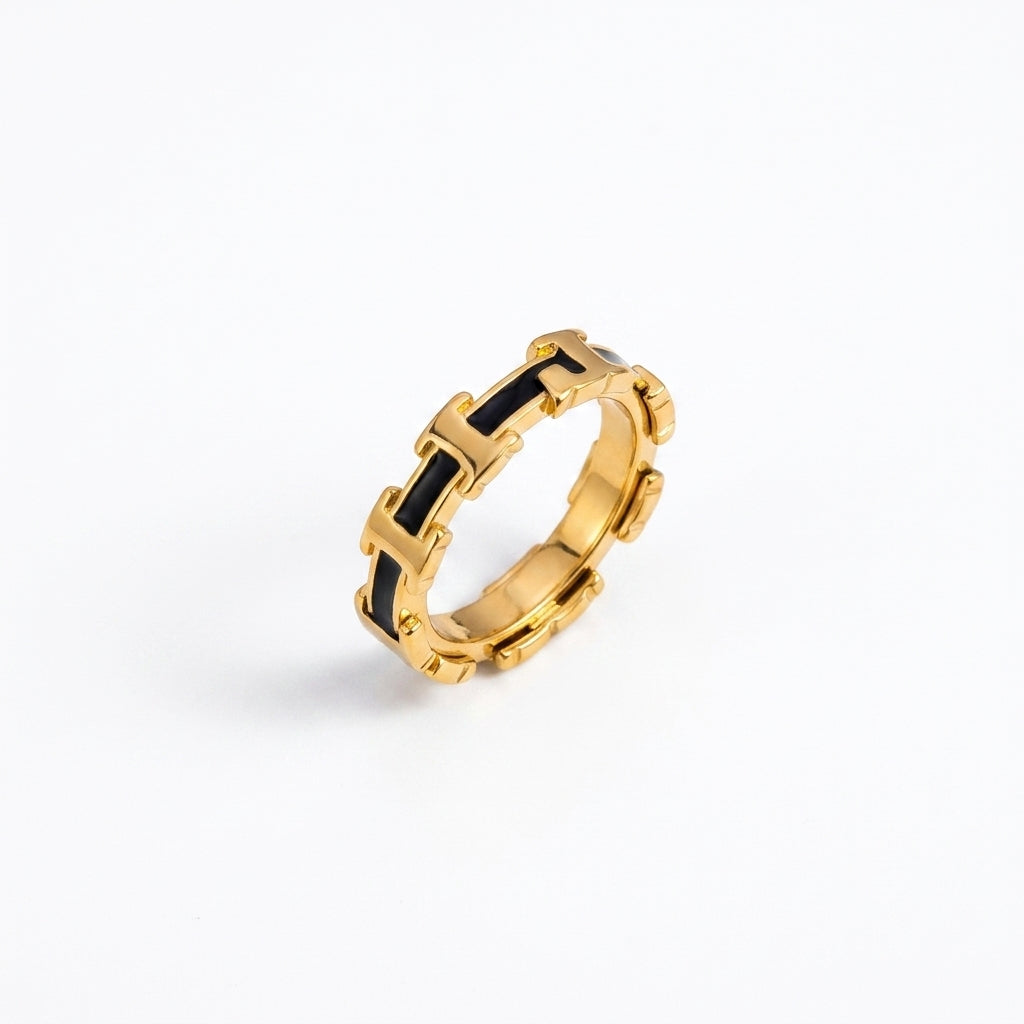 A gold ring with a repeating interlocking H-pattern design filled with black inlay, shown on a clean white background.