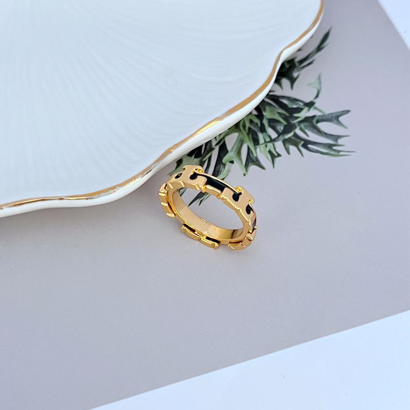 Clean, angled shot of the ring on a plain background, highlighting the sculpted serif 'T' shape and the vibrant enamel fill.