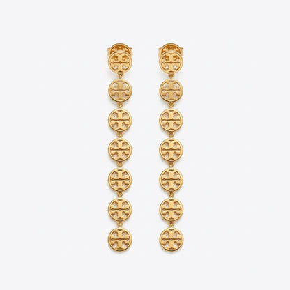 A pair of gold dangle earrings featuring a vertical chain of oval links, each engraved with the signature interlocking Tory Burch logo, set against a plain light gray background.
