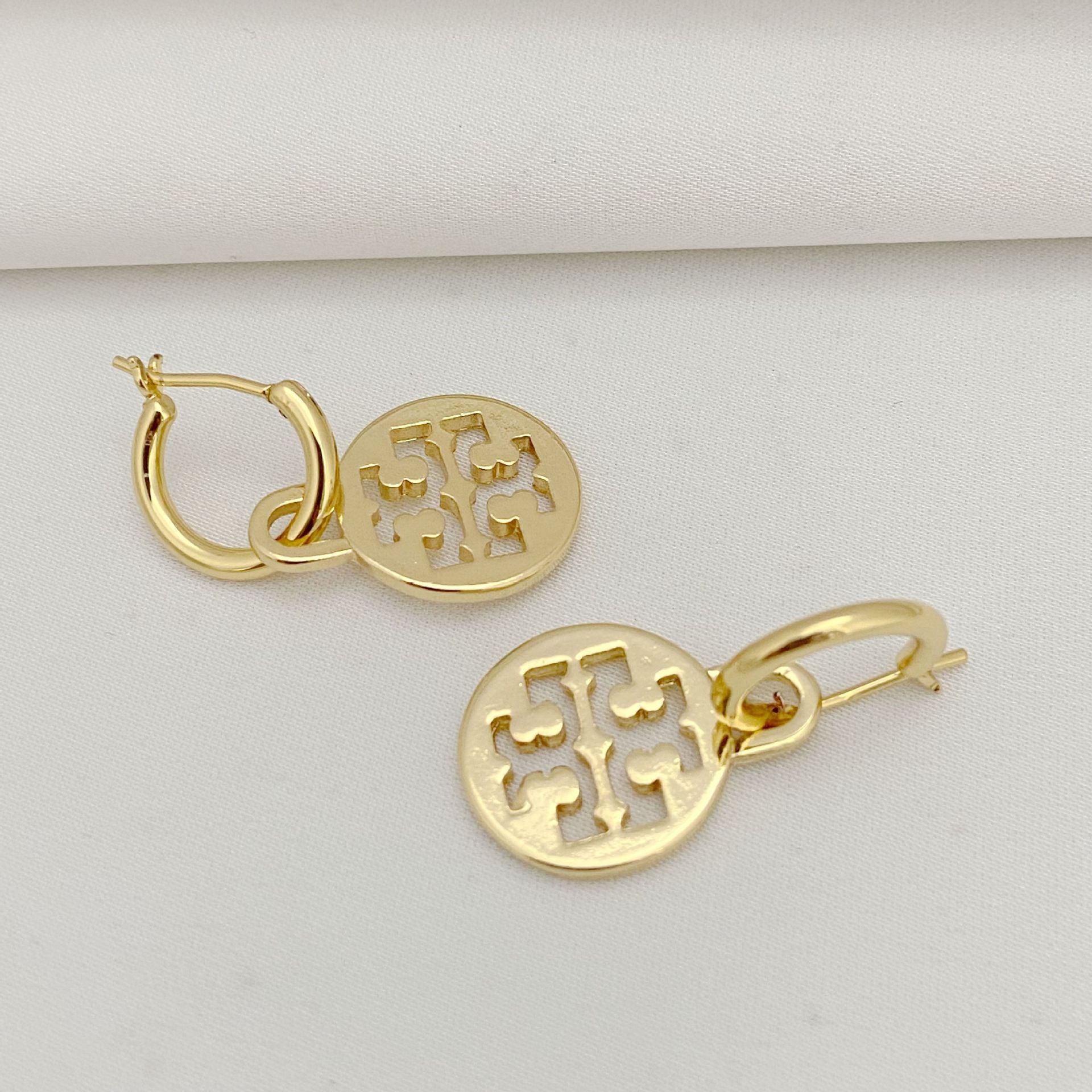 Gold hoop earrings with intricate designs on a light gray background
