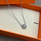 Necklace laid flat on a dark, non-reflective surface (black velvet or charcoal slate), making the crystal-covered logo and chain gleam dramatically.