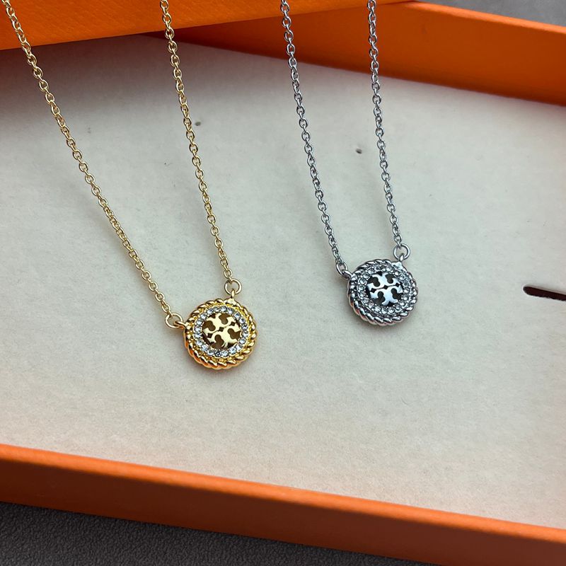 Necklace laid flat on a dark, non-reflective surface (black velvet or charcoal slate), making the crystal-covered logo and chain gleam dramatically.