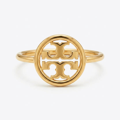 A gold ring featuring a circular openwork design with the interlocking Tory Burch logo at the center, set against a clean white background.