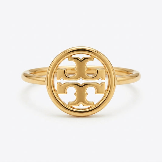 A gold ring featuring a circular openwork design with the interlocking Tory Burch logo at the center, set against a clean white background.