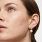 Close-up of a woman wearing pearl earrings with a white background
