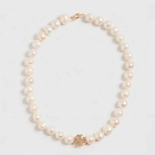 A strand of white freshwater pearls with a gold-tone cross-shaped charm and clasp, displayed on a light gray background.