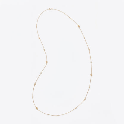 A delicate gold chain necklace featuring small, evenly spaced gold star charms, displayed on a clean, light gray background.