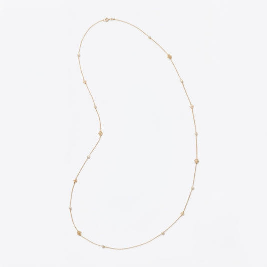 A delicate gold chain necklace featuring small, evenly spaced gold star charms, displayed on a clean, light gray background.