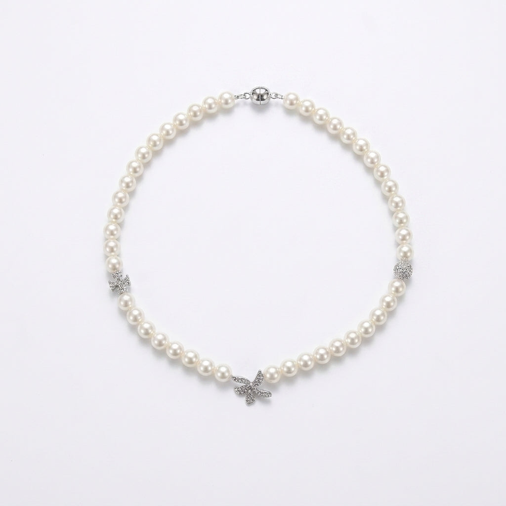 A pearl necklace with silver-toned butterfly and floral accents, displayed on a clean white background.