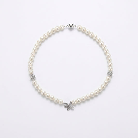 A pearl necklace with silver-toned butterfly and floral accents, displayed on a clean white background.