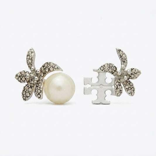 A pair of silver-toned stud earrings on a light gray background. One earring features a white pearl surrounded by small clear rhinestones in a floral shape, and the other shows the silver-toned puzzle-piece back.