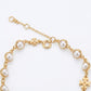 A gold chain bracelet featuring white faux pearls in bezel settings, a lobster clasp, an extender chain, and a small gold cross charm, shown on a plain white background.