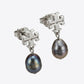 Pair of silver earrings with black pearls on a white background