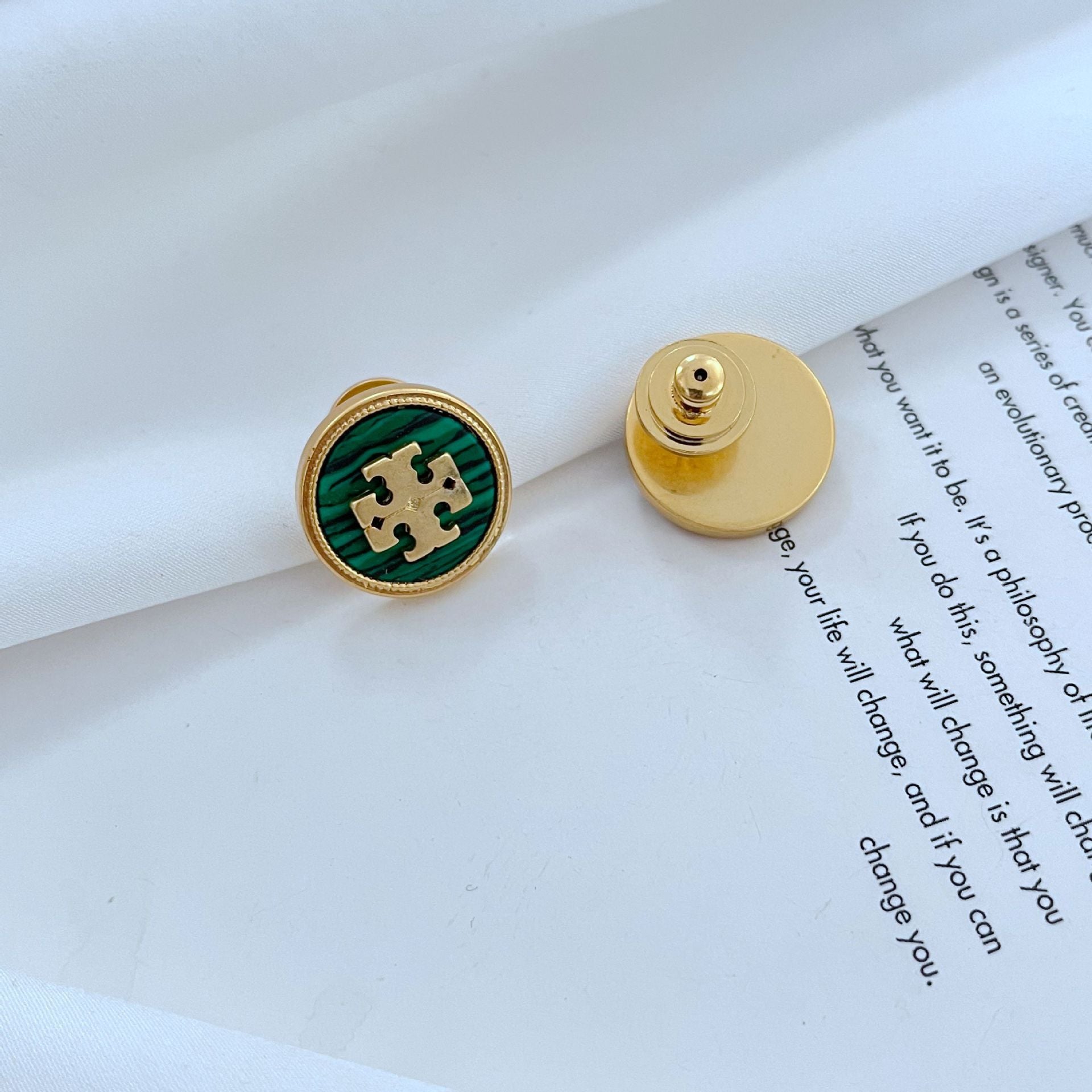 Gold and green earring on a book page