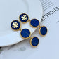 Blue and gold earrings on a white plate with a magazine background