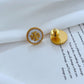 Gold earring with a logo on a white surface