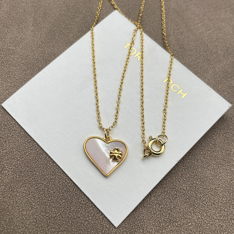 The necklace and earrings displayed together on a soft, light background (gray velvet or linen), showcasing the matching heart designs and iridescent pearl finish