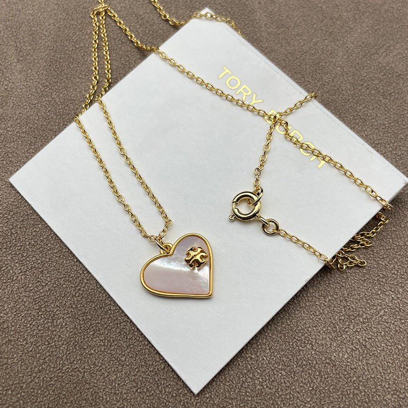 Close-up focusing on the heart shape, highlighting the natural iridescent play of color in the mother of pearl and the gold-tone setting.