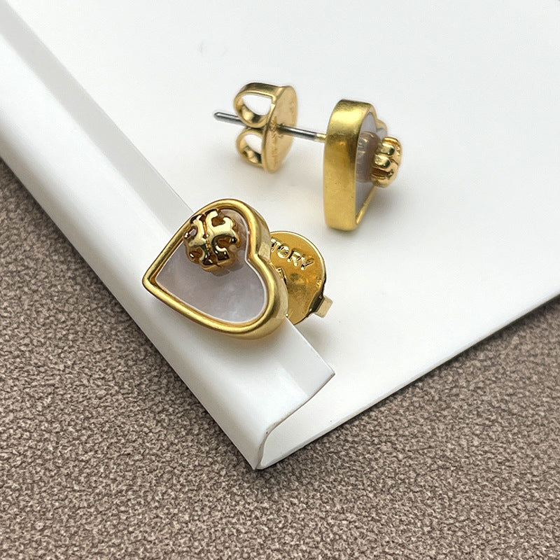 Close-up focusing on the heart shape, highlighting the natural iridescent play of color in the mother of pearl and the gold-tone setting.