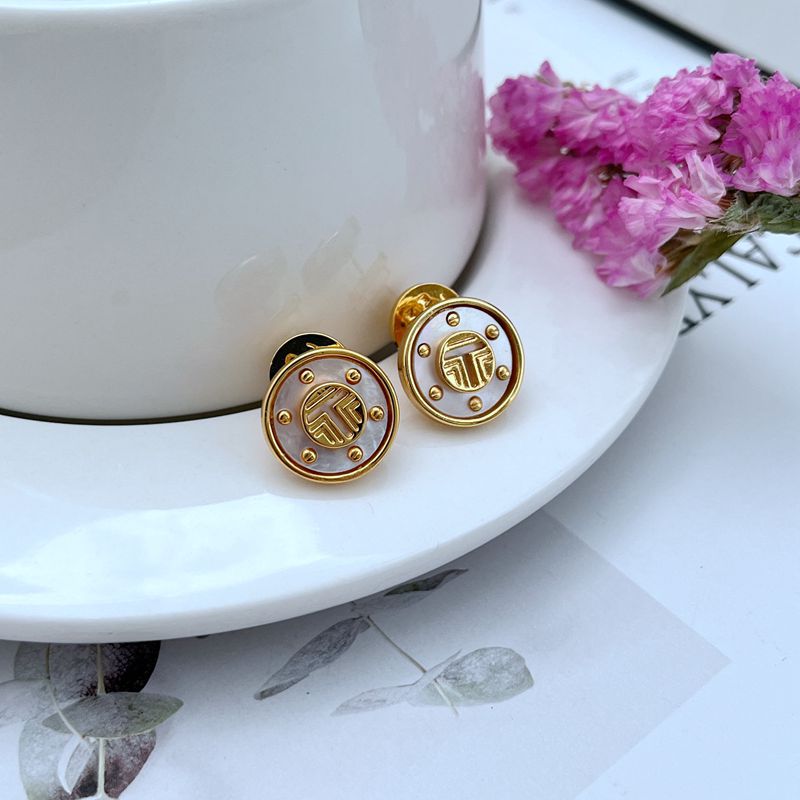 Clean shot of a single stud against a soft, neutral background, showcasing the beautiful iridescent colors of the mother-of-pearl and the gold setting.
