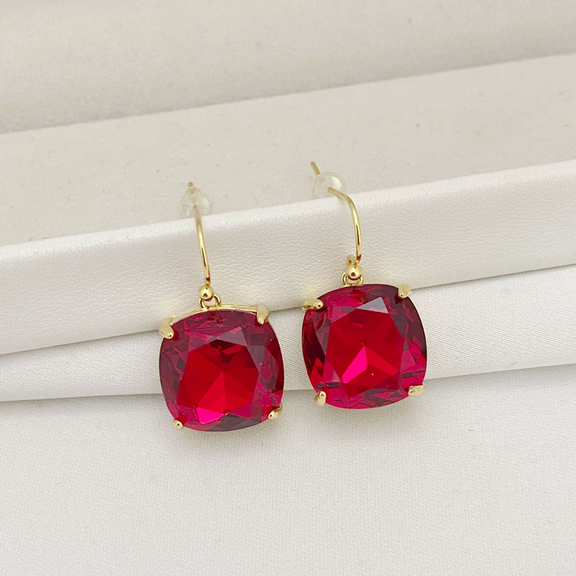 Gold earrings with red gemstones on a white surface
