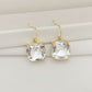 Gold earrings with clear gemstones on a white surface