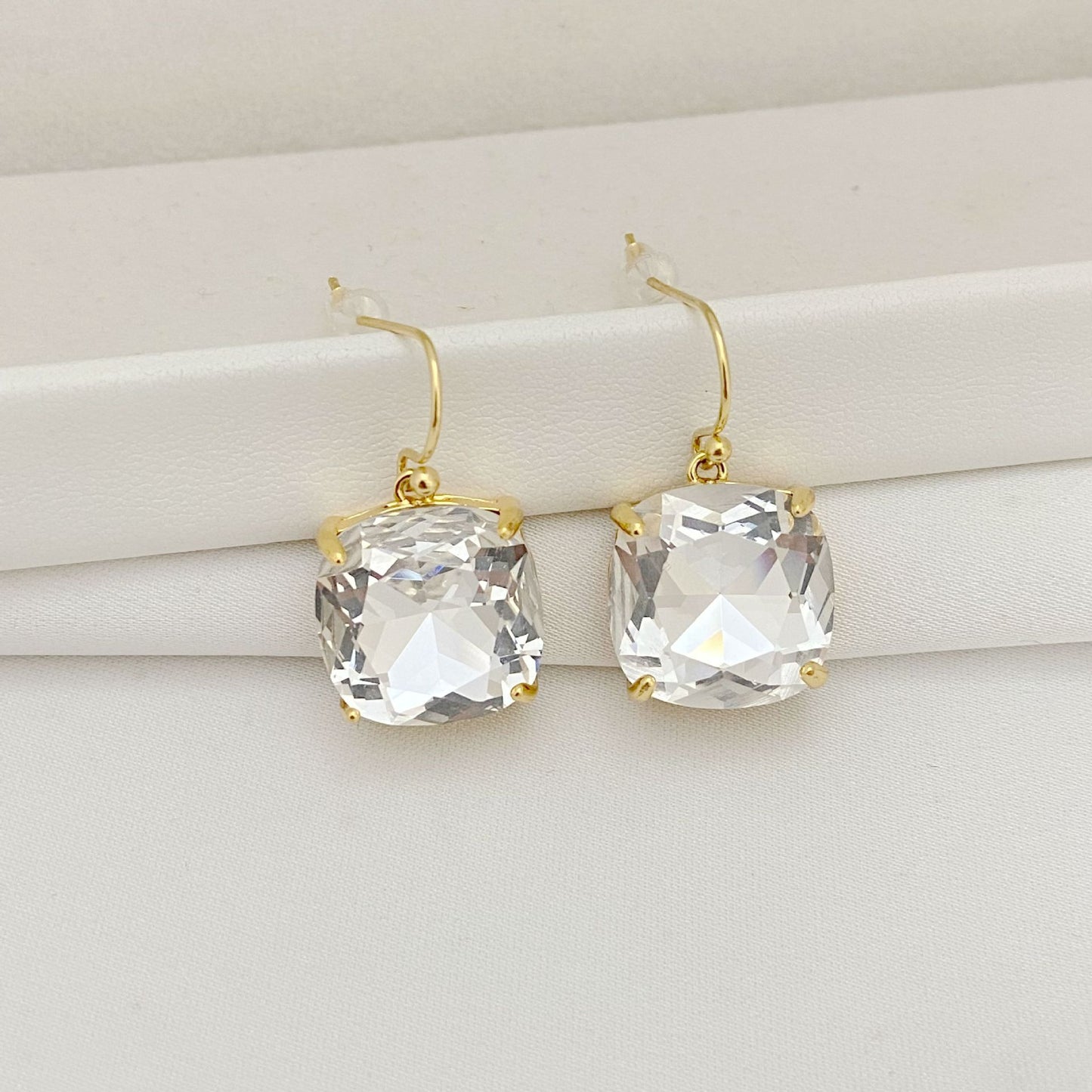 Gold earrings with clear gemstones on a white surface
