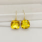 Gold earrings with yellow gemstones on a white background