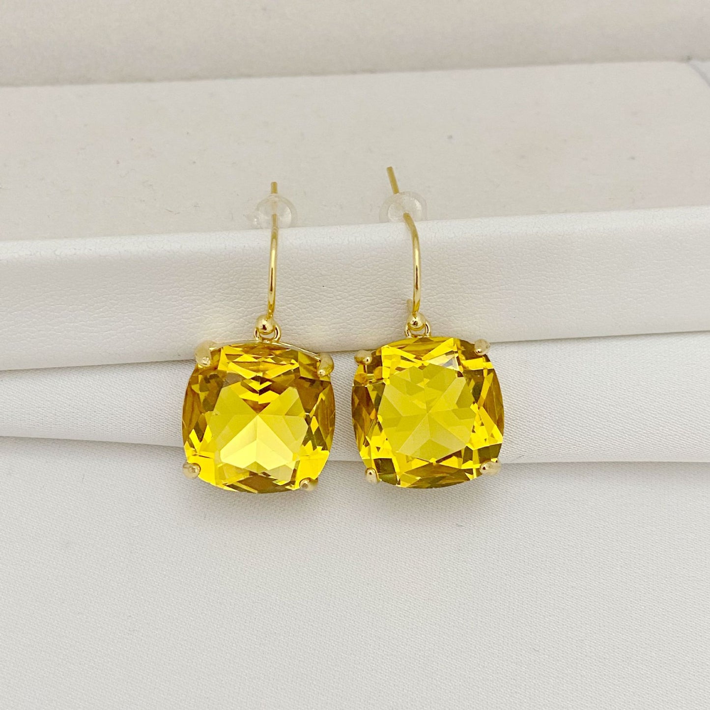 Gold earrings with yellow gemstones on a white background