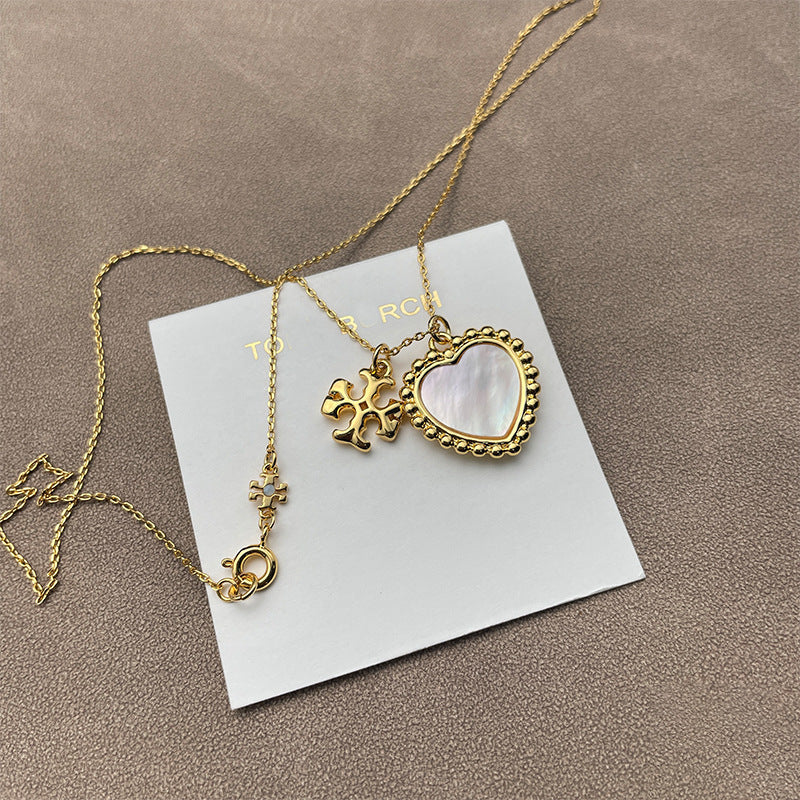 Close-up focused on the heart and Double T charms side-by-side, highlighting their shapes, polished finish, and any engraved details.