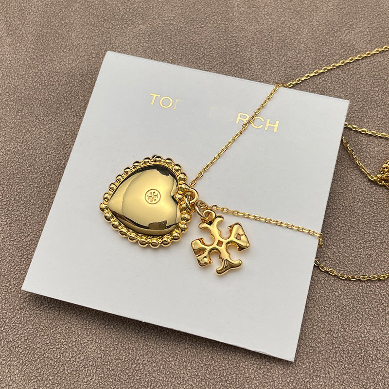 Close-up focused on the heart and Double T charms side-by-side, highlighting their shapes, polished finish, and any engraved details.