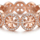 A close-up of a rose gold band featuring the interlocking Tory Burch logo surrounded by a halo of small clear stones, set against a clean white background.