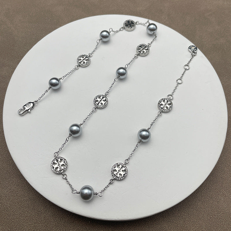 Necklace laid flat on a muted, textured background (e.g., gray slate or linen), highlighting the contrast between the organic pearl and the sparkling pave details.