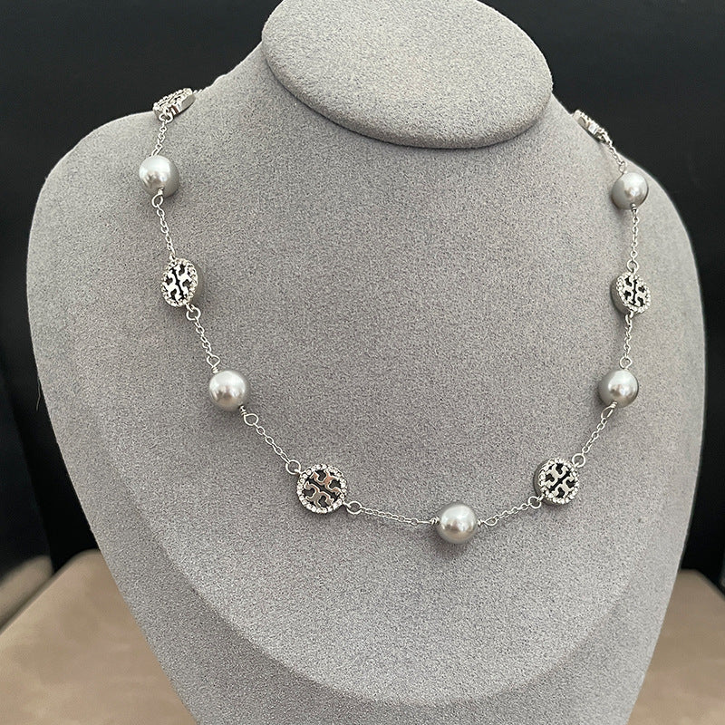 The necklace worn with both a crisp white shirt (day) and a simple black top (evening) to demonstrate its versatile elegance.