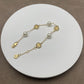 Bracelet laid flat on a soft, neutral background (light gray suede or linen), highlighting the pearl luster and gold chain detailing.