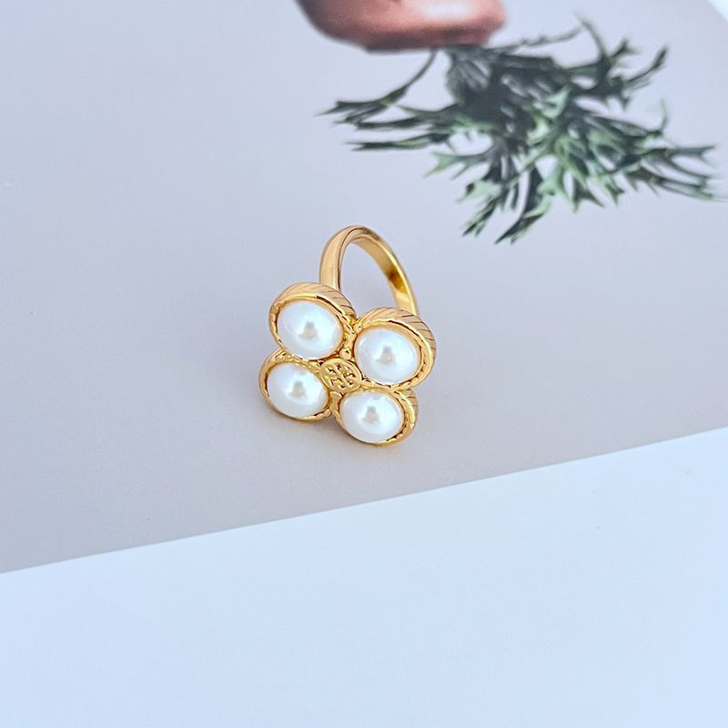 Clean shot of the ring on a simple background, showcasing the clover shape and the four pearls.